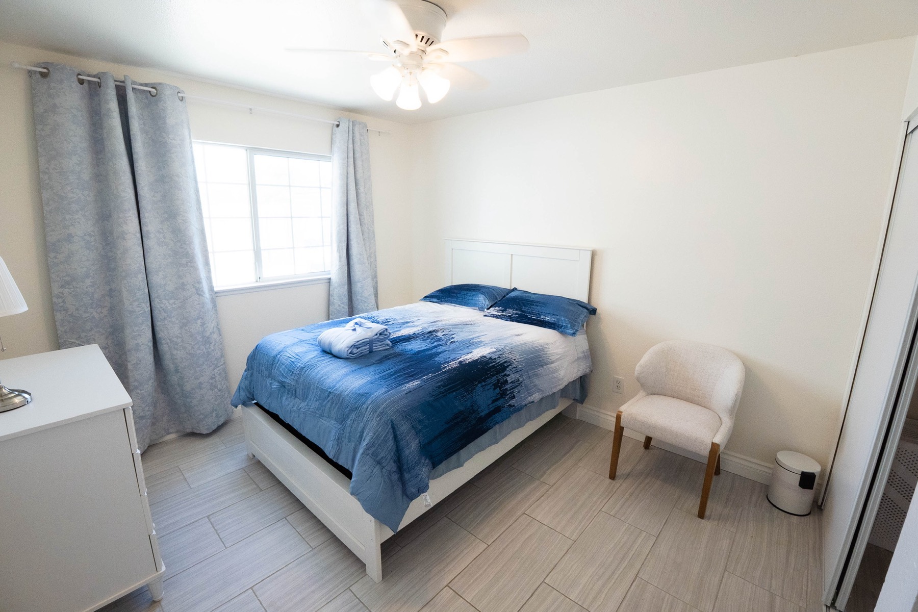 A calm, private bedroom with soft blue tones and natural light