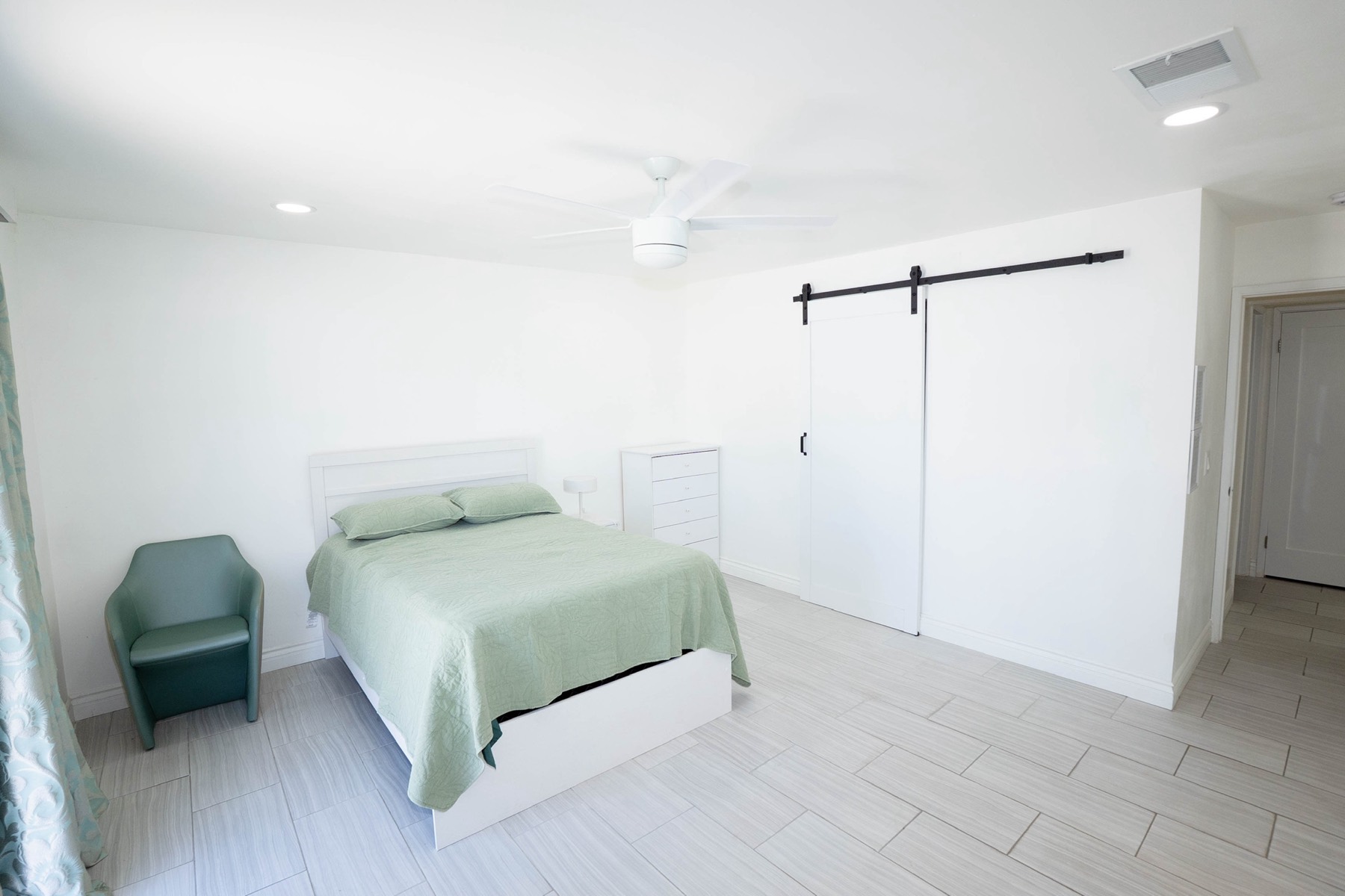 A bright private bedroom with a barn-door closet